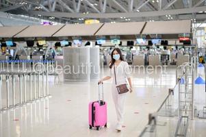 una donna viaggiatrice indossa una maschera protettiva nell'aeroporto internazionale, viaggia sotto la pandemia covid-19, viaggi di sicurezza, protocollo di allontanamento sociale, nuovo concetto di viaggio normale foto