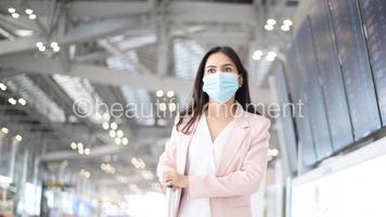 una donna d'affari indossa una maschera protettiva nell'aeroporto internazionale, viaggia sotto la pandemia covid-19, viaggi di sicurezza, protocollo di allontanamento sociale, nuovo concetto di viaggio normale foto