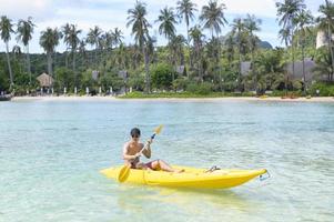 un giovane uomo sportivo che va in kayak sull'oceano in una giornata di sole foto