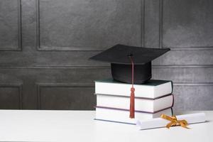 berretto di laurea con libri sulla scrivania bianca, priorità bassa di istruzione