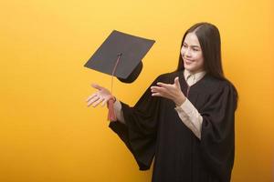 ritratto di bella donna felice in abito di laurea su sfondo giallo foto