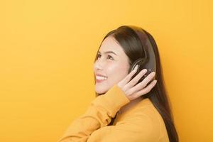 la donna amante della musica si diverte con l'auricolare su sfondo giallo foto