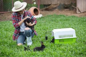 giovane contadina che tiene un coniglio nella fattoria dei conigli e divertiti con il suo animale domestico foto