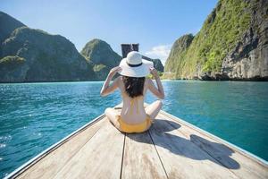 Vista della donna in costume da bagno godendo sulla tradizionale barca tailandese a coda lunga sulla bellissima montagna e sull'oceano, isole phi phi, tailandia foto