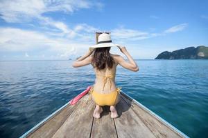 Vista della donna in costume da bagno godendo sulla tradizionale barca tailandese a coda lunga sulla bellissima montagna e sull'oceano, isole phi phi, tailandia