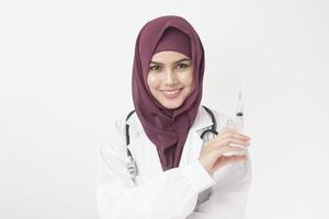 bella donna medico con hijab sta tenendo la siringa su sfondo bianco