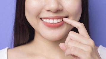 giovane bella donna sorridente sta mostrando e indicando i suoi denti bianchi dritti sani su sfondo viola studio foto