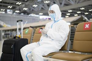 un uomo asiatico indossa una tuta dpi in aeroporto internazionale, viaggi di sicurezza, protezione covid-19, concetto di allontanamento sociale