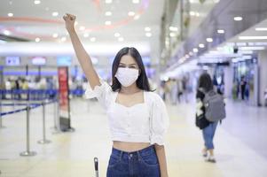 una donna viaggiatrice indossa una maschera protettiva nell'aeroporto internazionale, viaggia sotto la pandemia covid-19, viaggi di sicurezza, protocollo di allontanamento sociale, nuovo concetto di viaggio normale foto