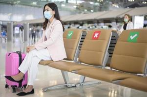 una donna d'affari indossa una maschera protettiva nell'aeroporto internazionale, viaggia sotto la pandemia covid-19, viaggi di sicurezza, protocollo di allontanamento sociale, nuovo concetto di viaggio normale foto