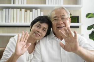 un anziano asiatico felice è una videochiamata, si rilassa a casa, sorride nonni pensionati anziani sani, concetto di tecnologia dei nonni più anziani foto