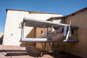 piccolo aeroplano d'epoca appoggiato al muro dell'edificio foto