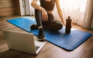 frullato proteico o una bottiglia d'acqua e sta usando un laptop. concetto di sport e ricreazione. foto