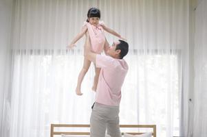 un padre sano tiene in braccio una figlia felice e carina che vola e gioca in aereo insieme a casa nei fine settimana, concetto di famiglia. foto