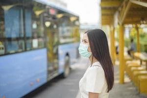 bella donna indossa una maschera alla fermata dell'autobus foto