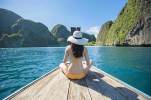 Vista della donna in costume da bagno godendo sulla tradizionale barca tailandese a coda lunga sulla bellissima montagna e sull'oceano, isole phi phi, tailandia