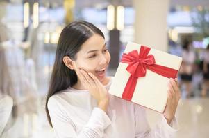 donna che tiene una confezione regalo nel centro commerciale, il ringraziamento e il concetto di natale. foto