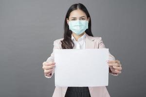 donna d'affari con maschera chirurgica tiene in mano carta bianca