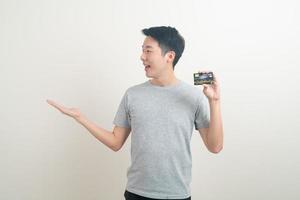 giovane asiatico in possesso di carta di credito foto