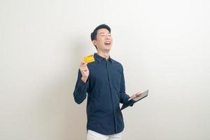 Ritratto di giovane uomo asiatico in possesso di carta di credito e tablet foto