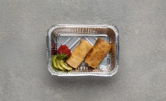 fast food in una scatola di alluminio su sfondo grigio. un cibo sano da vicino