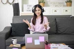 una giovane e bella donna che indossa l'auricolare sta effettuando una videoconferenza tramite computer a casa, concetto di tecnologia aziendale. foto