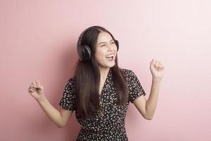 la donna amante della musica si diverte con l'auricolare su sfondo rosa foto