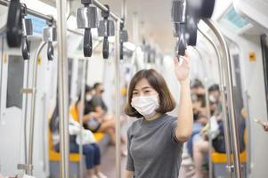 la giovane donna indossa una maschera protettiva in metropolitana, protezione covid-19, viaggi di sicurezza, nuova normalità, distanziamento sociale, trasporti di sicurezza, viaggi in condizioni di pandemia. foto