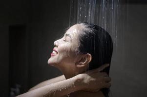 giovane bella donna che si lava i capelli in un bagno a casa foto