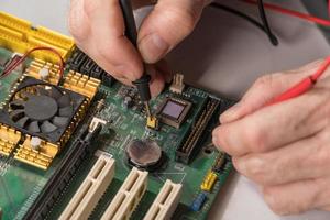 il tecnico elettronico sta testando un chip per computer. riparazione pc foto