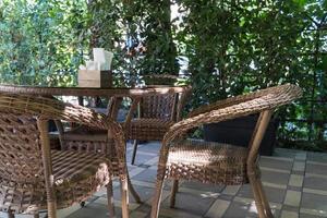 tavoli e sedie di vimini nella caffetteria estiva all'aperto con aiuole foto
