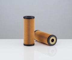 due filtri automobilistici di forma cilindrica di colore arancione su sfondo bianco foto