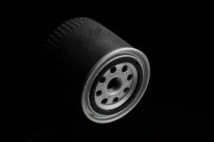 filtro automobilistico metallico di forma cilindrica con gocce d'acqua su sfondo nero foto