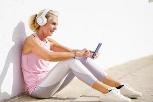 donna sportiva matura che si prende una pausa per controllare un'app di fitness sul suo smartphone