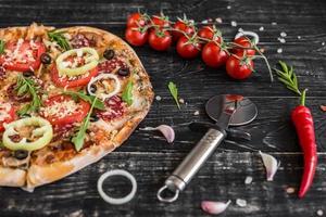 pizza tradizionale italiana, verdure, ingredienti su sfondo scuro foto