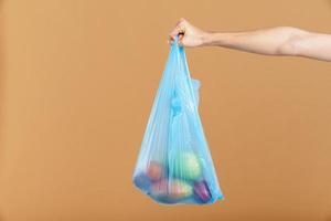 donna che tiene il sacchetto della spazzatura di plastica blu con frutta foto