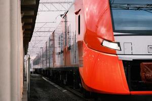 rosso con un treno pendolare ad alta velocità grigio in partenza dalla stazione ferroviaria foto