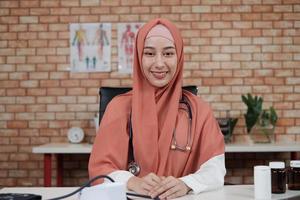 ritratto di una bella dottoressa, bella musulmana in uniforme con uno stetoscopio, sorridente e guardando la telecamera nella clinica dell'ospedale. una persona che ha esperienza nel trattamento professionale. foto