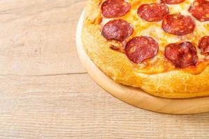 pizza ai peperoni su vassoio di legno foto