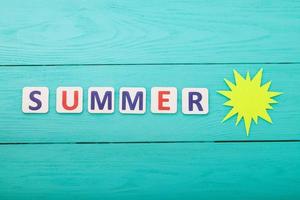 parola estate con sole di carta su sfondo di legno blu foto