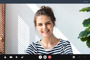 donna caucasica che guarda la fotocamera e sorride mentre effettua una videoconferenza in soggiorno, istruzione a distanza e lavoro da casa foto