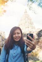 giovane donna attraente che prende selfie sul suo telefono mentre viaggia al tempio di Phnom Rung in Thailandia. foto