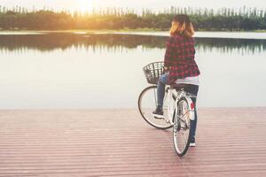 parte posteriore della giovane donna hipster in bicicletta con la bicicletta su un molo, rilassarsi godersi le vacanze estive. foto