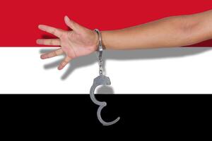 manette con la mano sulla bandiera dello yemen foto