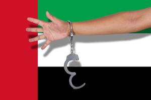 manette con la mano sulla bandiera degli emirati arabi uniti foto