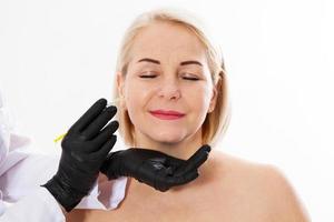 concetto di iniezione di botox ritratto del primo piano di una bella donna di mezza età e mani del medico che fanno l'iniezione di botox isolato su sfondo bianco. collagene. messa a fuoco selettiva foto