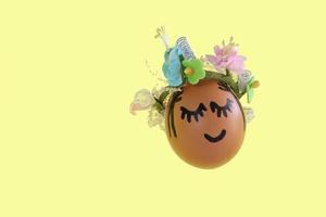 uovo di pasqua naturale con faccia dipinta divertente e ghirlanda di fiori dolci foto