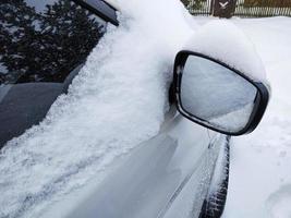 un'autovettura ricoperta di neve. specchietto laterale nella neve. foto