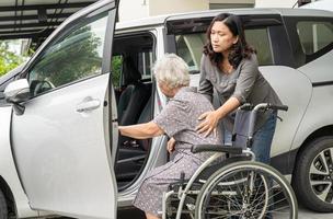 la figlia della badante aiuta e sostiene la paziente asiatica anziana o anziana della donna anziana prepararsi per raggiungere la sua macchina. foto