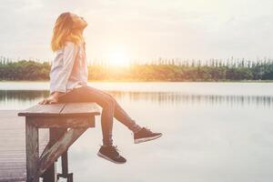 giovane bella donna hipster seduta sul lago rilassante con aria fresca. foto